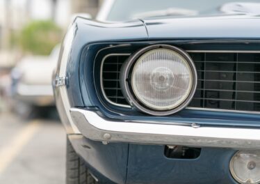 Close up of vintage old car with faded color and rust on the side