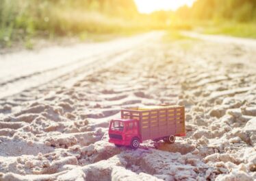 Toy retro truck on the road - symbol of cargo transportation